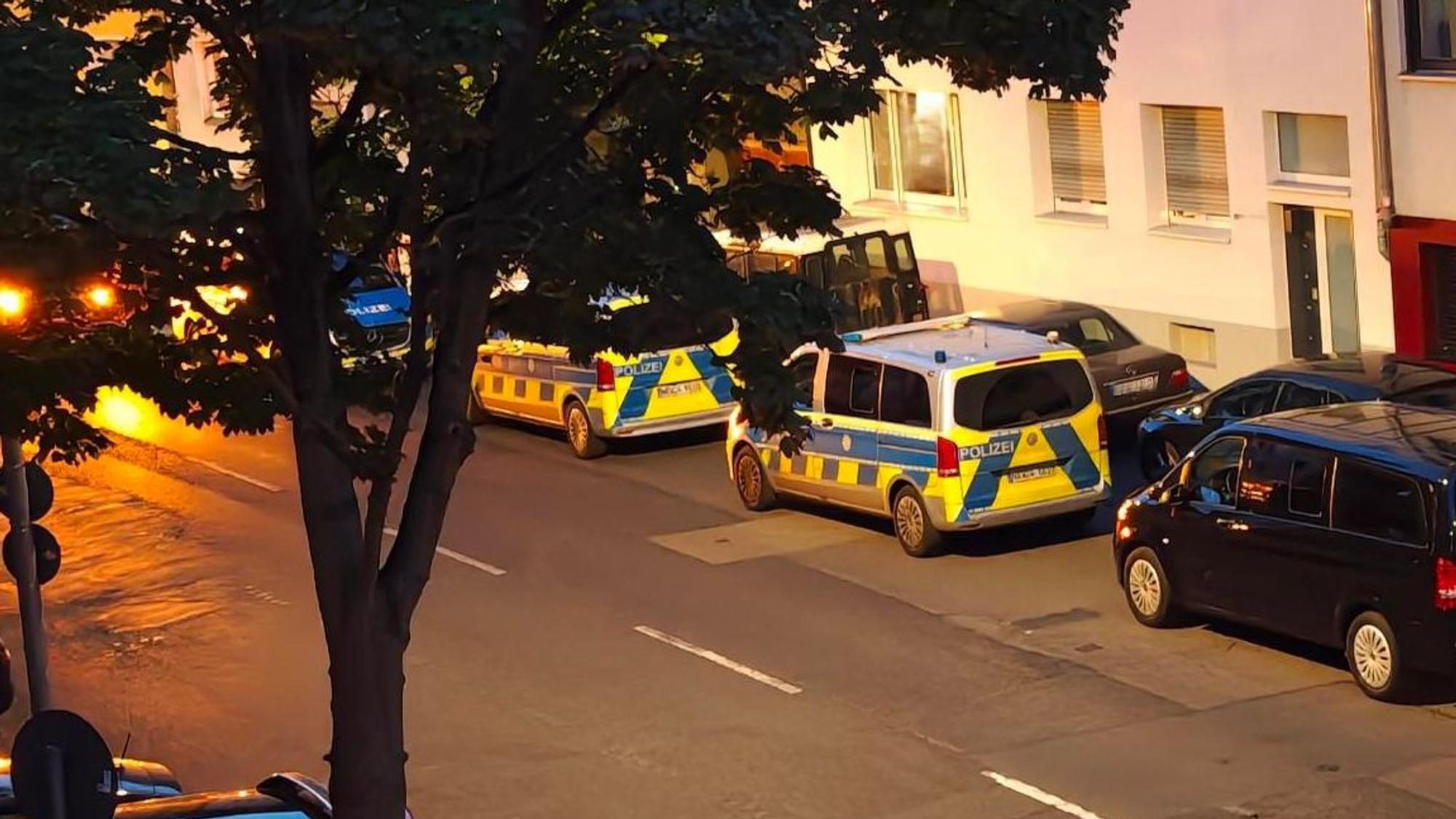 Mehrere Polizeifahrzeuge parken vor einer Häuserfront.