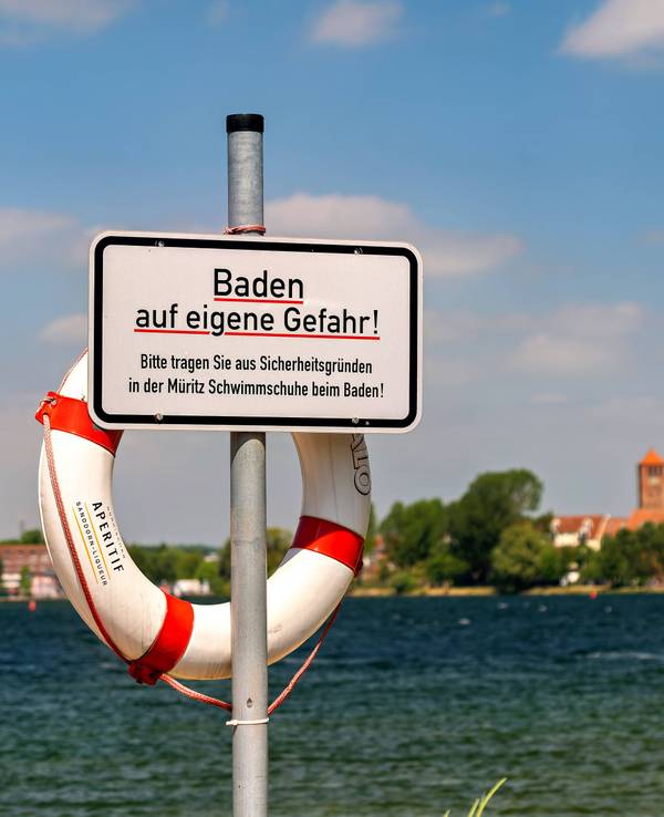 Ein Blick auf Waren Müritz in Mecklenburg-Vorpommern im Landkreis Mecklenburgische Seenplatte. m Vordergrund steht ein Schild mit dem Aufdruck „Baden auf eigene Gefahr“.
