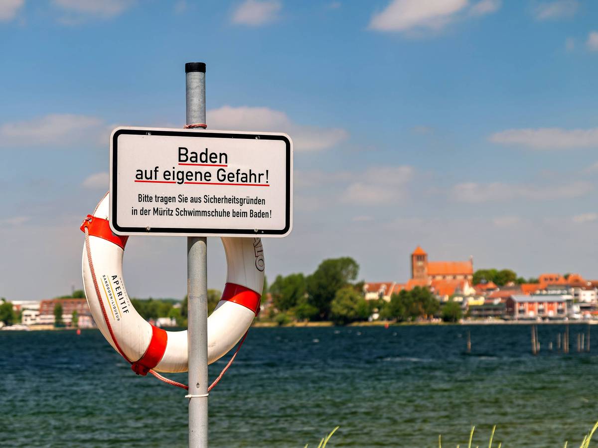 Ein Blick auf Waren Müritz in Mecklenburg-Vorpommern im Landkreis Mecklenburgische Seenplatte. m Vordergrund steht ein Schild mit dem Aufdruck „Baden auf eigene Gefahr“.