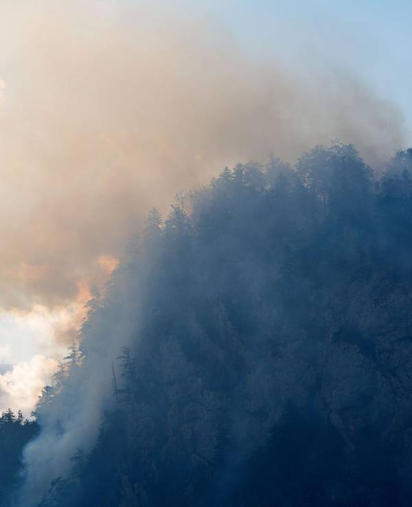 Ein Hubschrauber lässt zur Bekämpfung eines Brandes im Bergwald in den Chiemgauer Alpen Löschwasser ab.