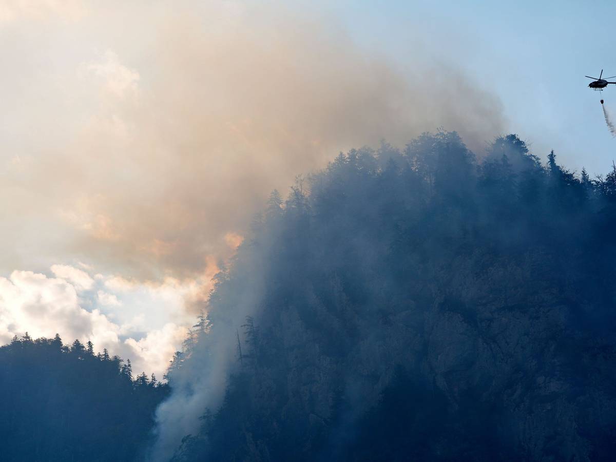 Ein Hubschrauber lässt zur Bekämpfung eines Brandes im Bergwald in den Chiemgauer Alpen Löschwasser ab.