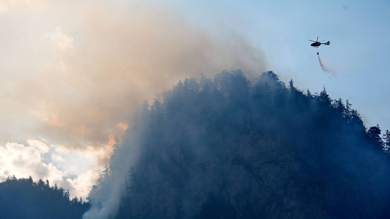 Ein Hubschrauber lässt zur Bekämpfung eines Brandes im Bergwald in den Chiemgauer Alpen Löschwasser ab.