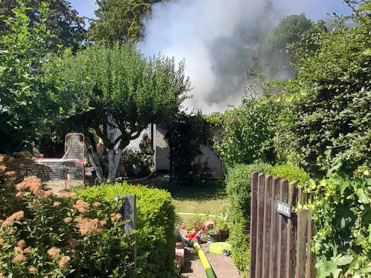 Von einem Garten aus ist aufsteigender Brandrauch zu sehen.
