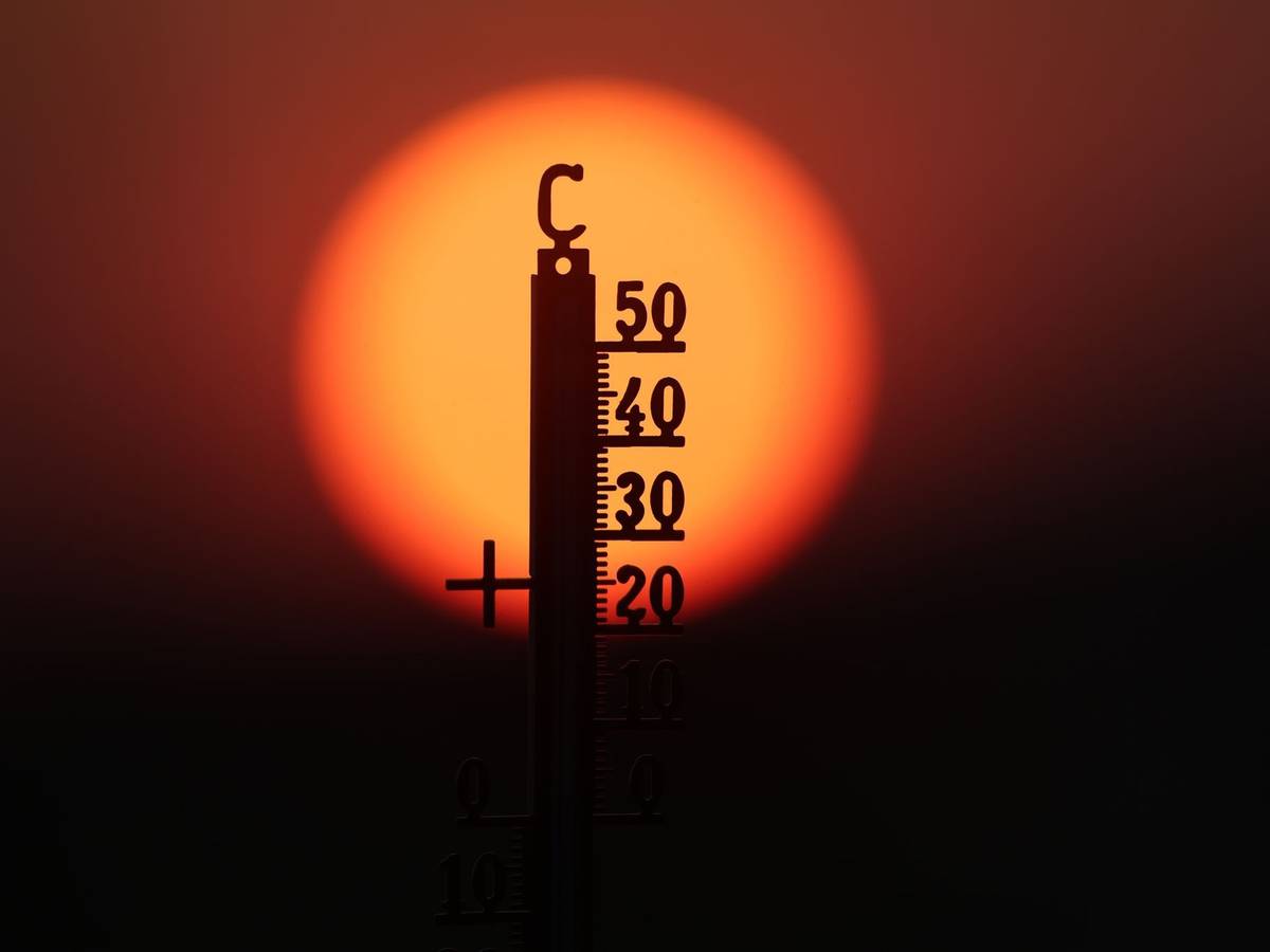 Hitze in Deutschland: Ein Thermometer vor einer rotglühenden Sonne