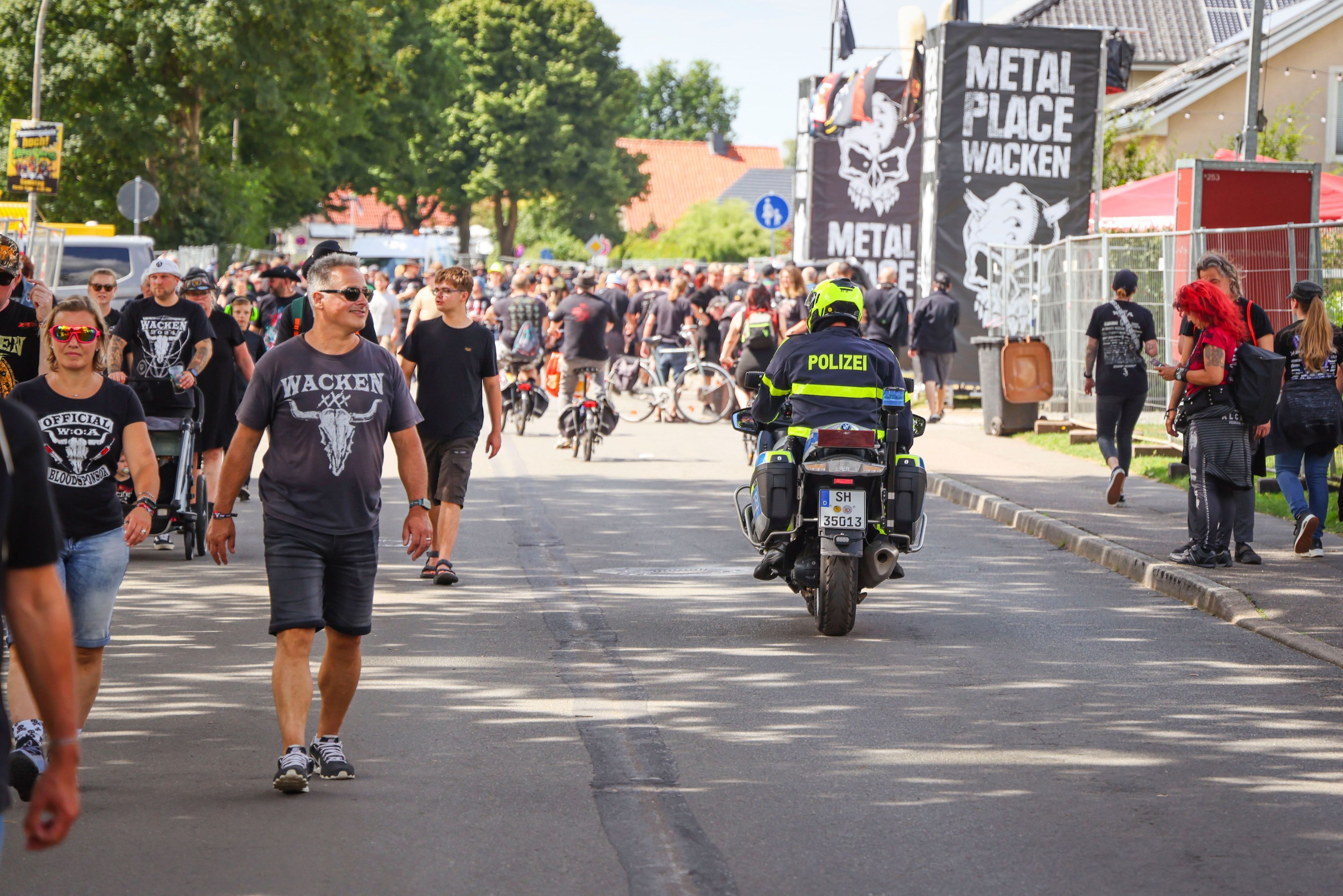 Ein Polizeibeamter fährt während des Wacken Open Air (W:O:A) mit einem Motorrad durch die Ortsmitte