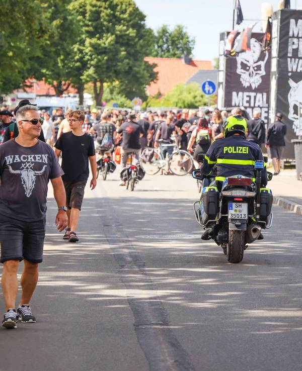 Ein Polizeibeamter fährt während des Wacken Open Air (W:O:A) mit einem Motorrad durch die Ortsmitte
