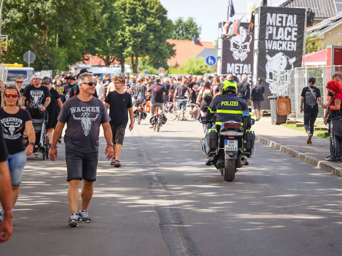 Ein Polizeibeamter fährt während des Wacken Open Air (W:O:A) mit einem Motorrad durch die Ortsmitte