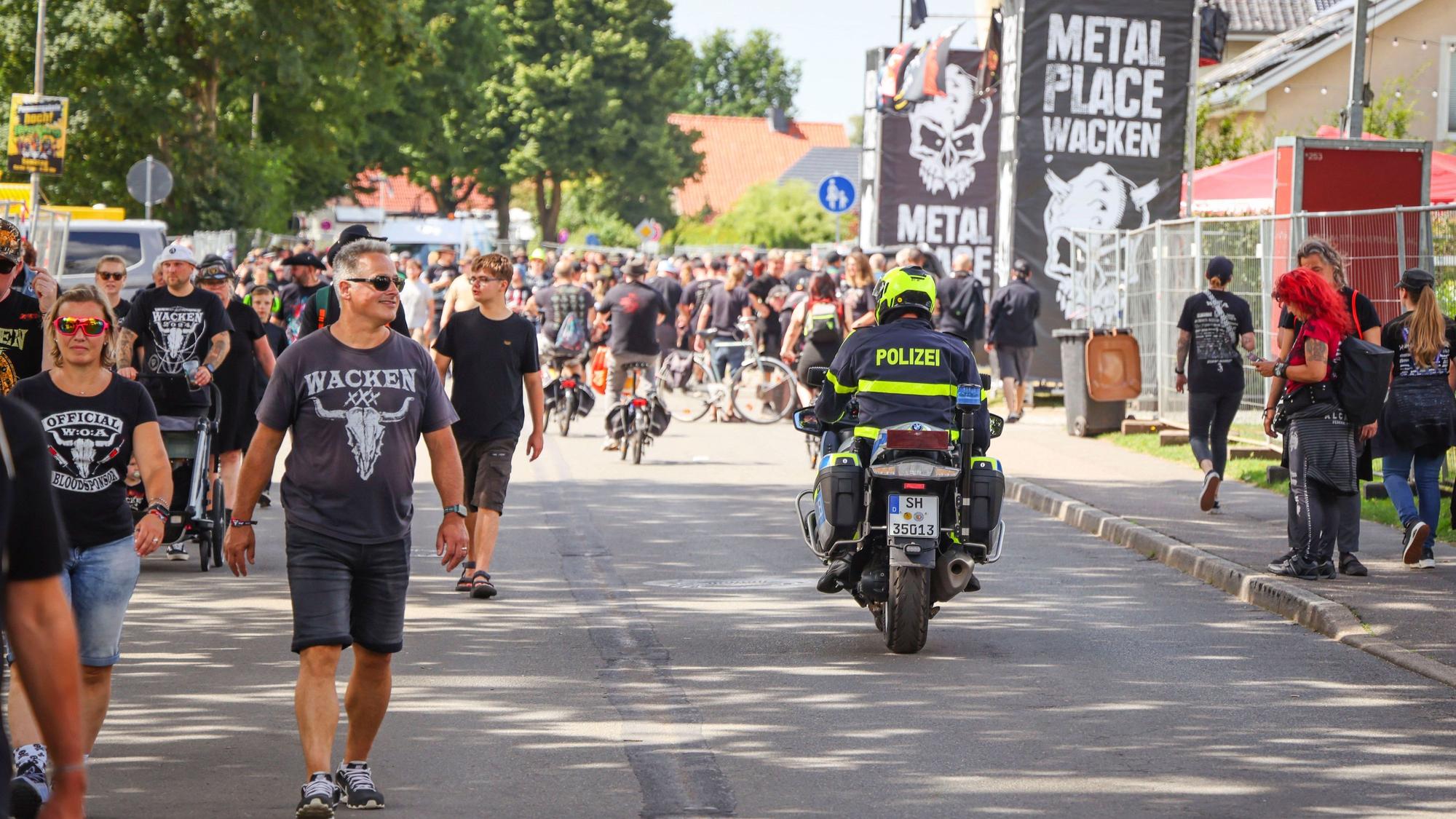 Ein Polizeibeamter fährt während des Wacken Open Air (W:O:A) mit einem Motorrad durch die Ortsmitte