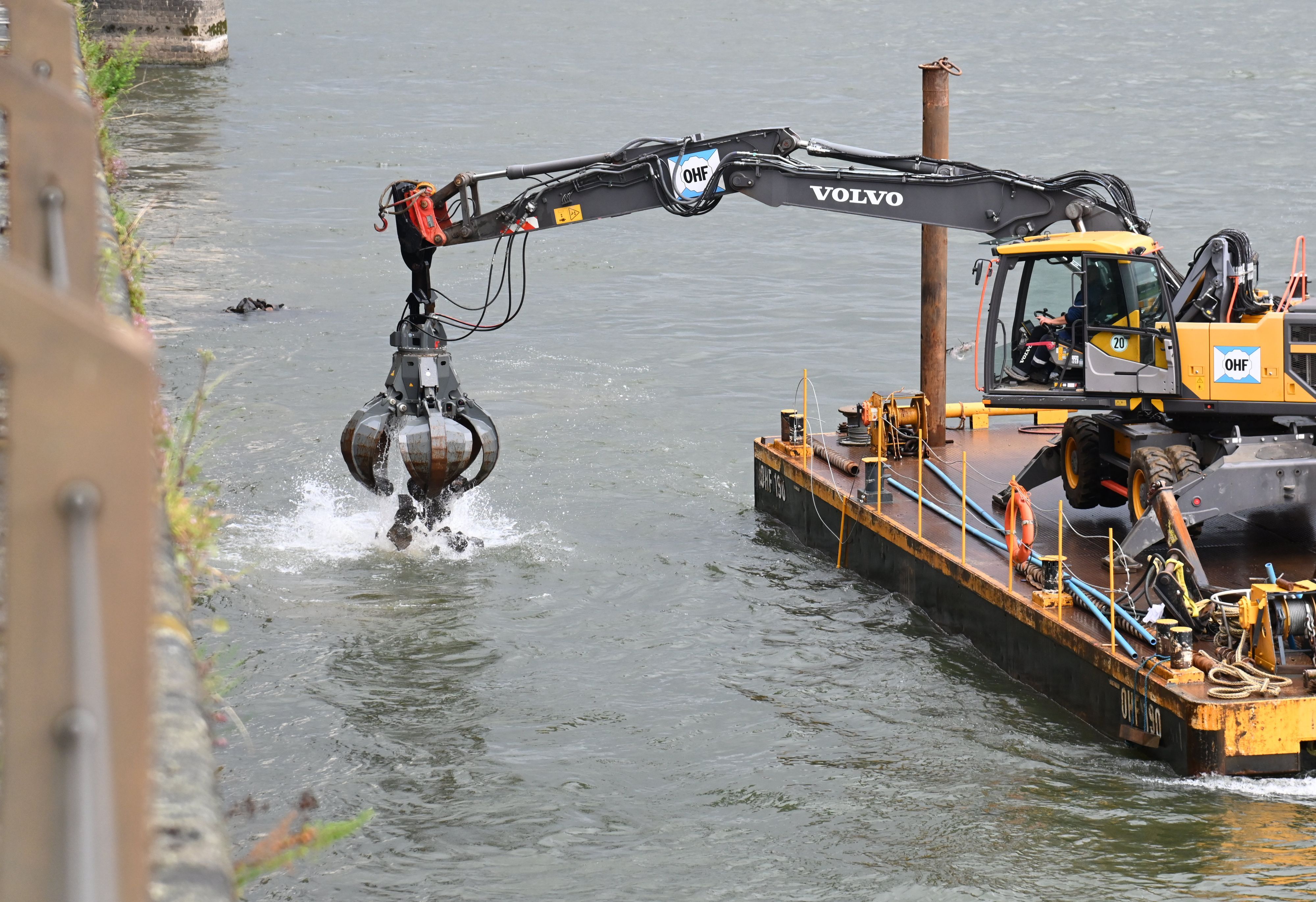 Am Rheinufer vor dem Rheinauhafen liegen Schiffe einer Wasserbaufirma vor der Kaimauer vor Anker und führen Arbeiten durch.