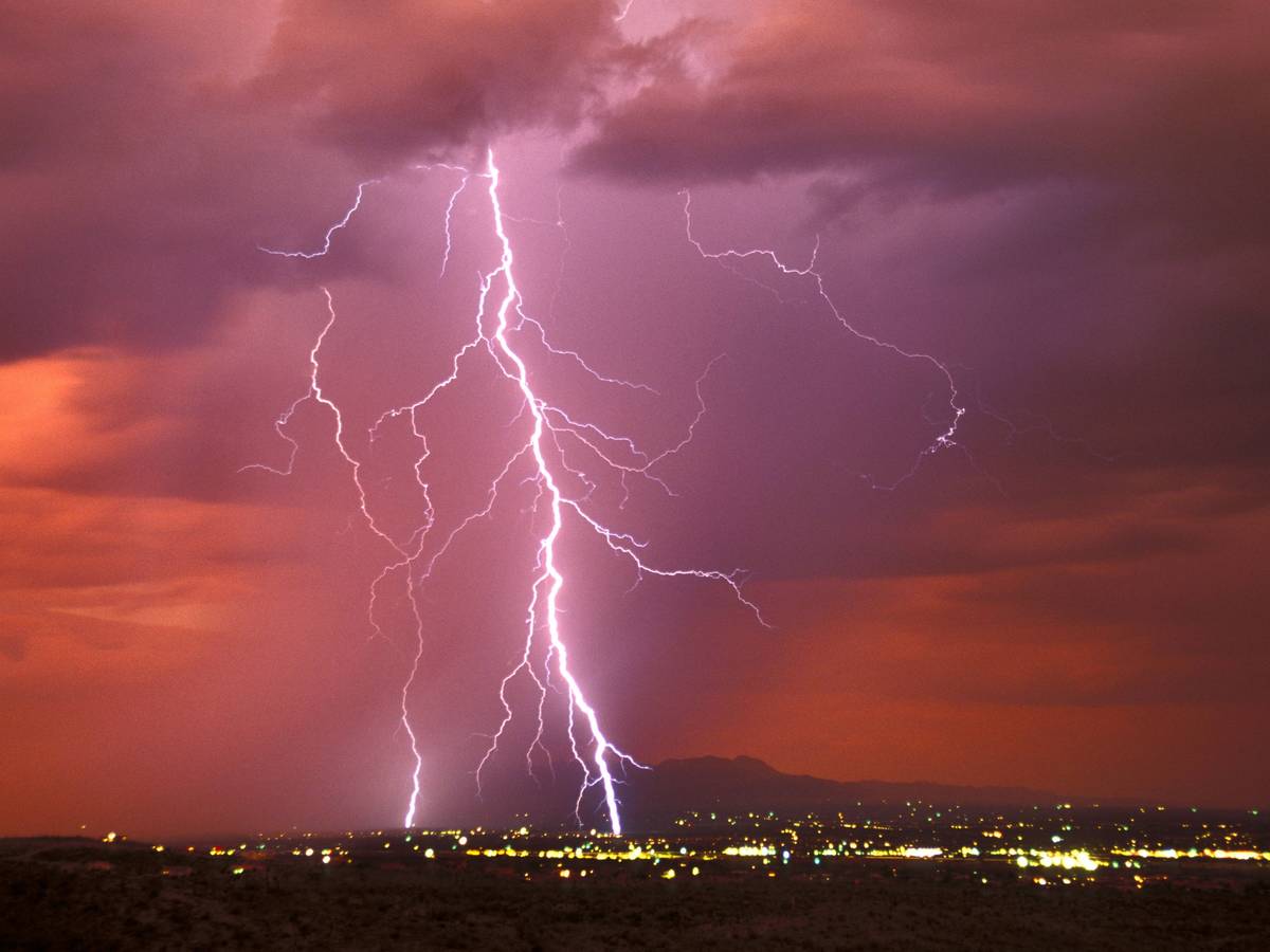 Ein riesiger Blitz zuckt vom Himmel auf eine Stadt hernieder
