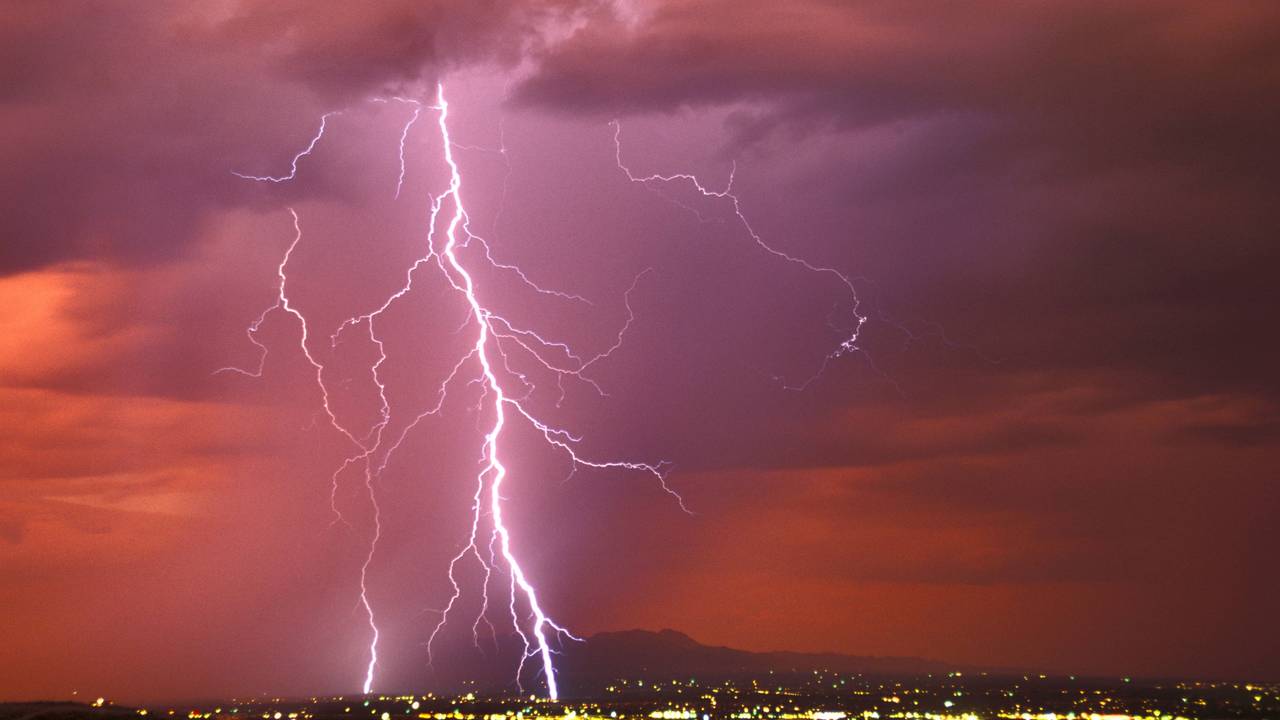 Ein riesiger Blitz zuckt vom Himmel auf eine Stadt hernieder