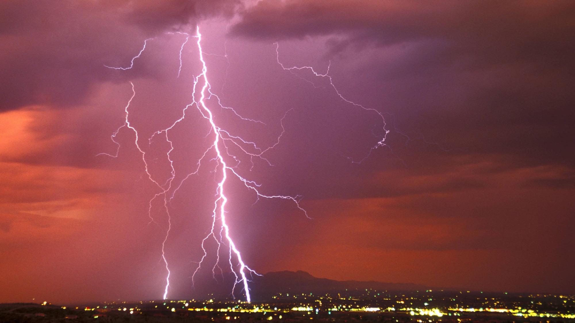 Ein riesiger Blitz zuckt vom Himmel auf eine Stadt hernieder
