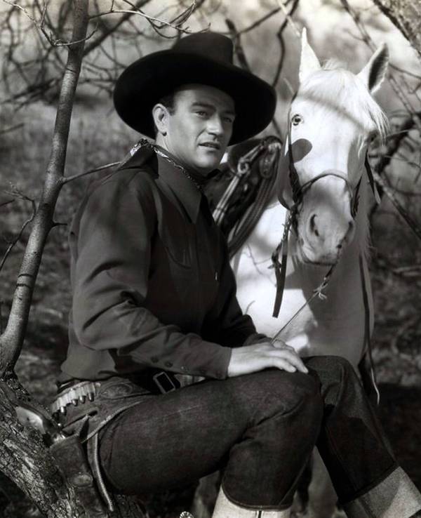 John Wayne als Westernheld mit Pferd.