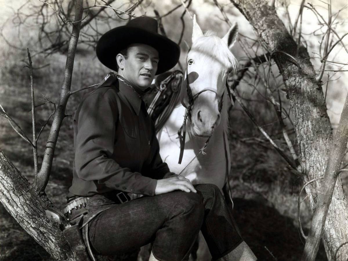 John Wayne als Westernheld mit Pferd.