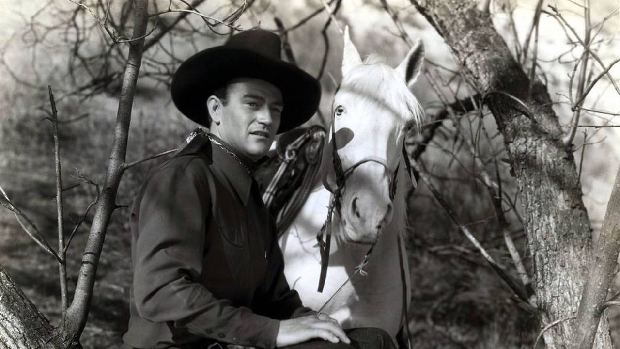 John Wayne als Westernheld mit Pferd.