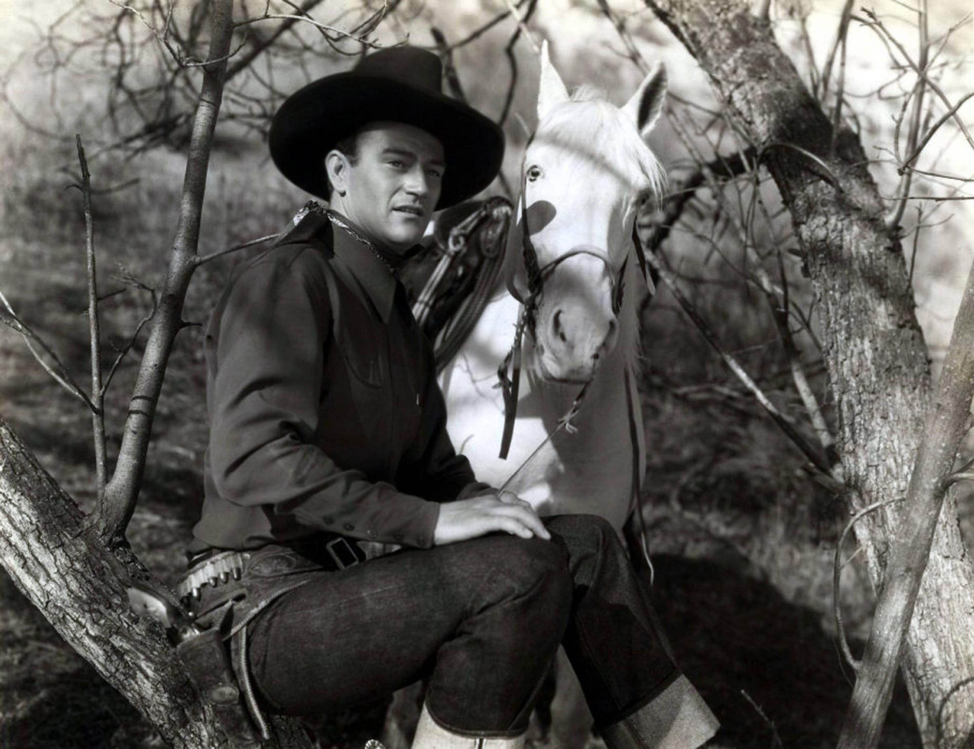 John Wayne als Westernheld mit Pferd.