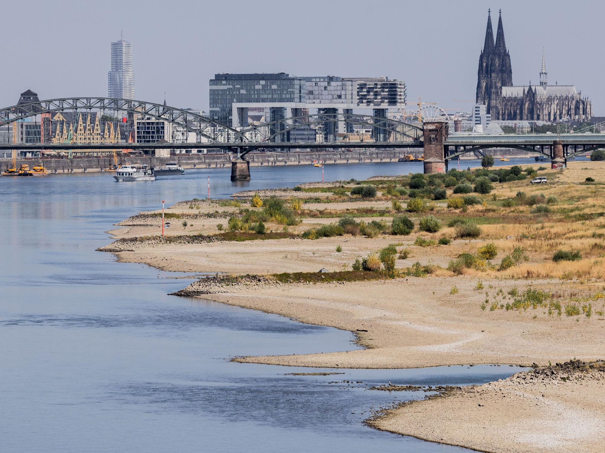 Binnenschiffe fahren bei Niedrigwasser vor der Kulisse des Kölner Doms über den Rhein.