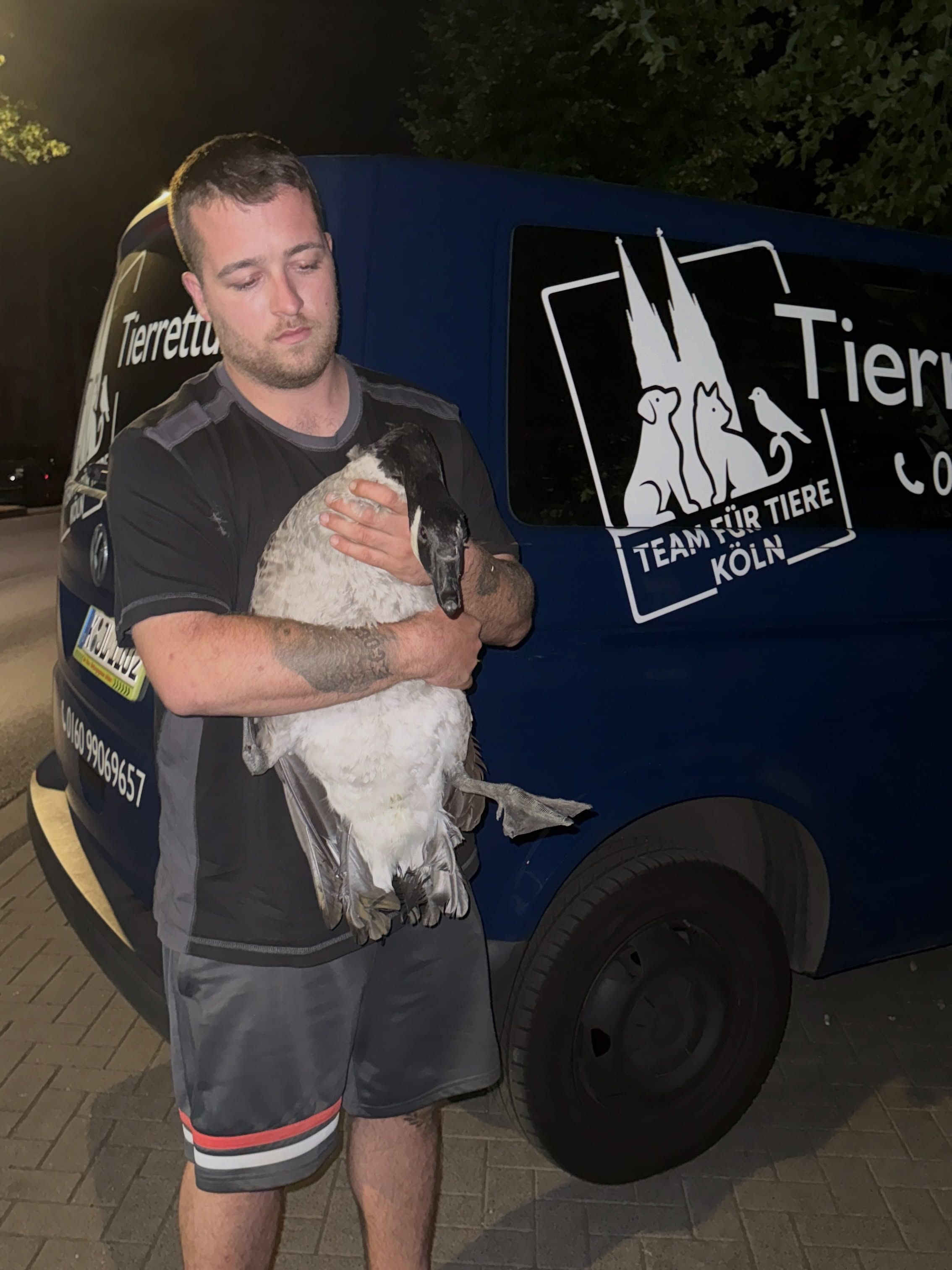 Ein Mann hält eine Gans auf dem Arm.