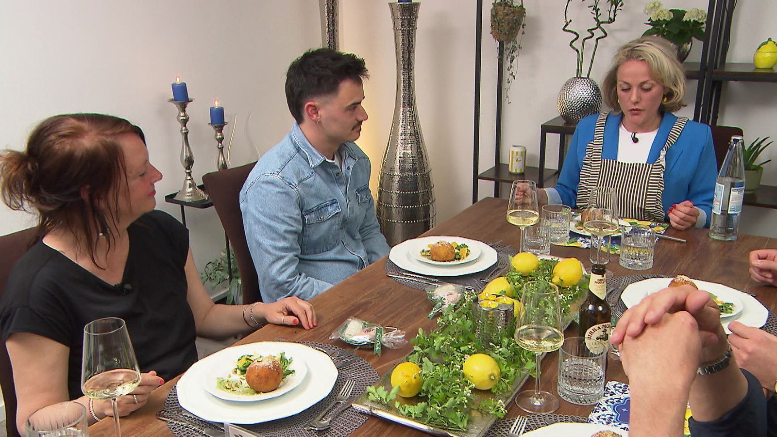 Was Shirin (rechts) erst nach der Vorspeise auffällt: Sie hat sich mit der Schürze an den Tisch gesetzt.
 (Bild: RTL)
