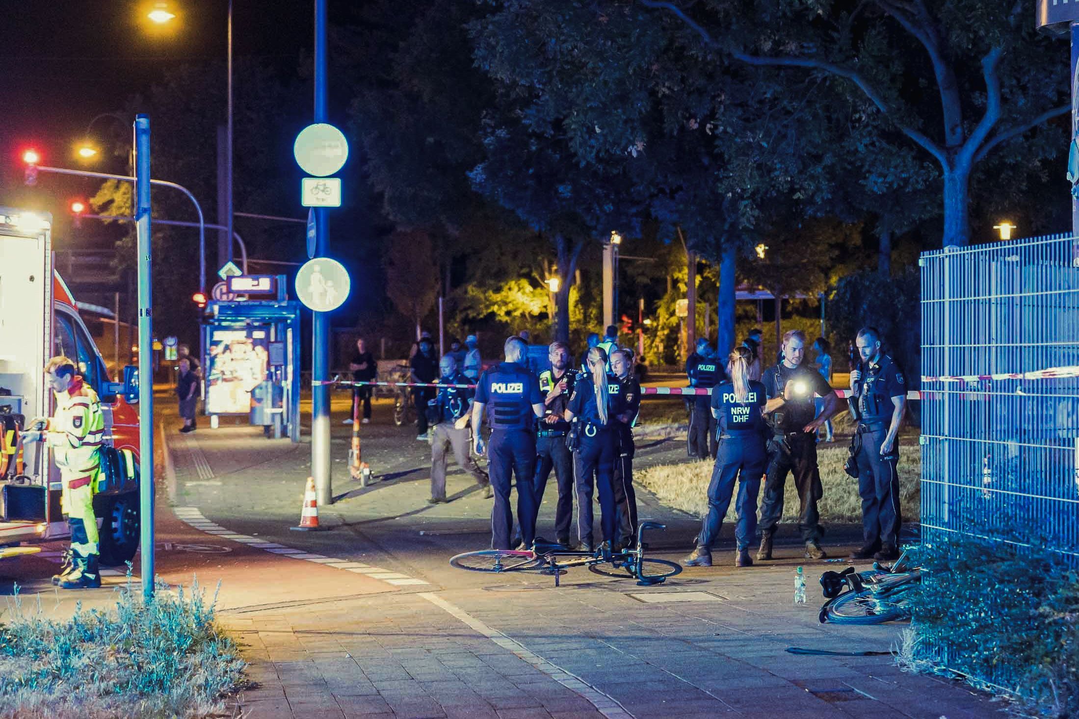 Die Polizei und Rettungskräfte sind in Köln Mülheim nach Schüssen auf offener Straße an einem Tatort beschäftigt.