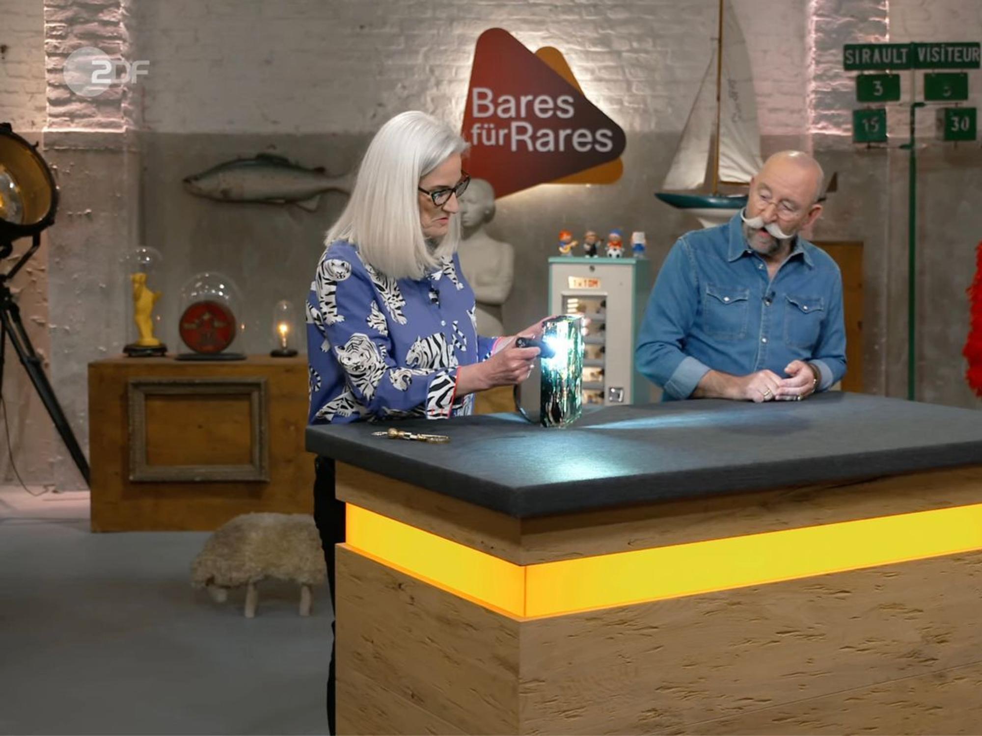 Horst Lichter war sofort begeistert, als in der Mittwochsausgabe von „Bares für Rares“ (ZDF) ein außergewöhnliches Murano-Aquarium auf dem Expertentisch landete und dank der Taschenlampe die Details sichtbar wurden: „Das ist absolut der Hammer. Wunderschön.“ Im Händlerraum begann die Auktion überraschend zögerlich - samt „frechen“ Geboten ... (Bild: ZDF)