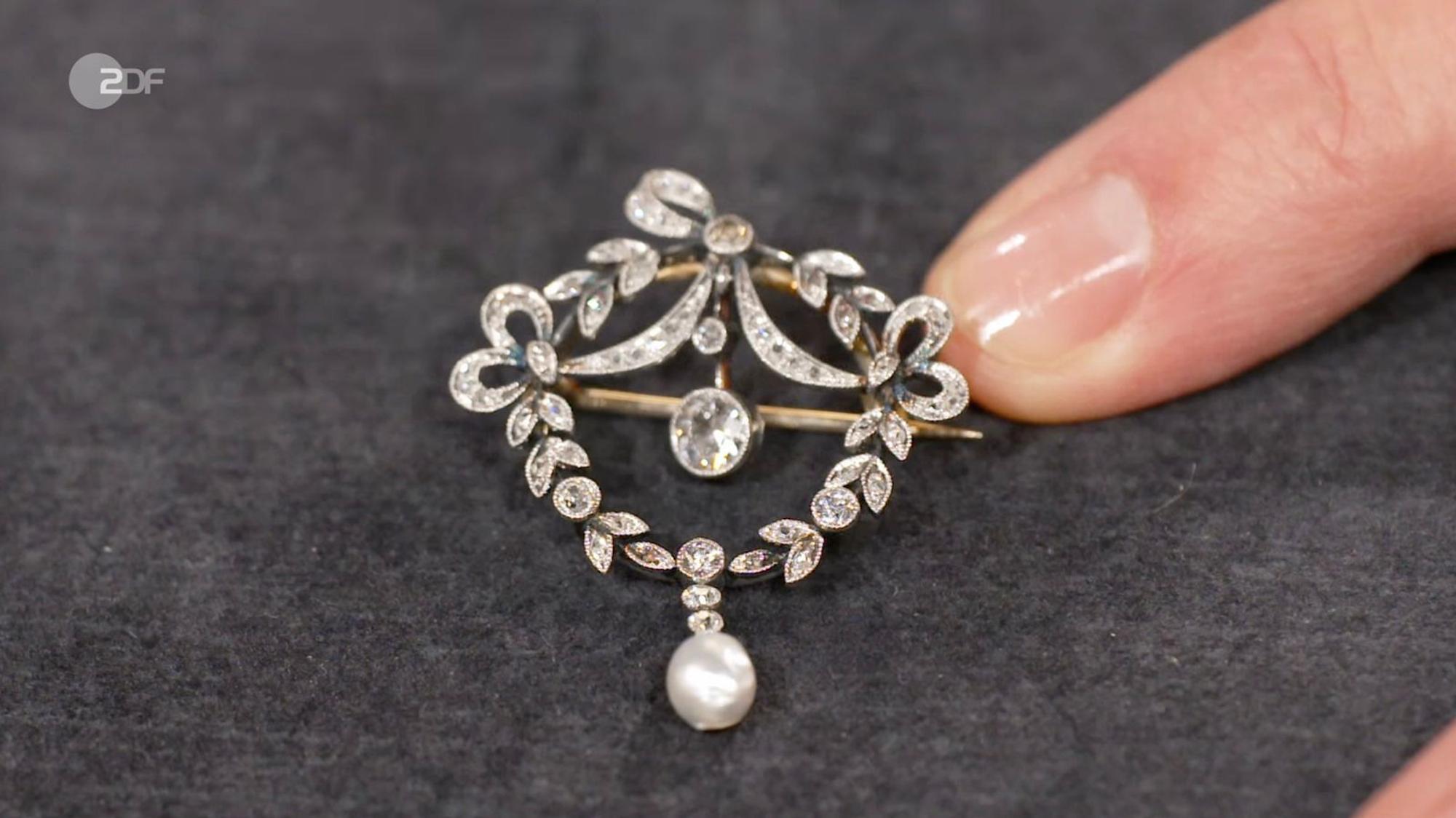 Eine Jugendstil-Brosche aus dem Familienbesitz datierte Heide Rezepa-Zabel auf 1900 bis 1910. Nach dem Wunschpreis von 1.000 Euro, schätzte sie das Schmuckstück aus Platin und 585er Gold mit Diamanten und Naturperle auf 800 bis 1.000 Euro. Im Händlerraum sicherte sich Sarah Schreiber die Brosche schließlich für 700 Euro. (Bild: ZDF)