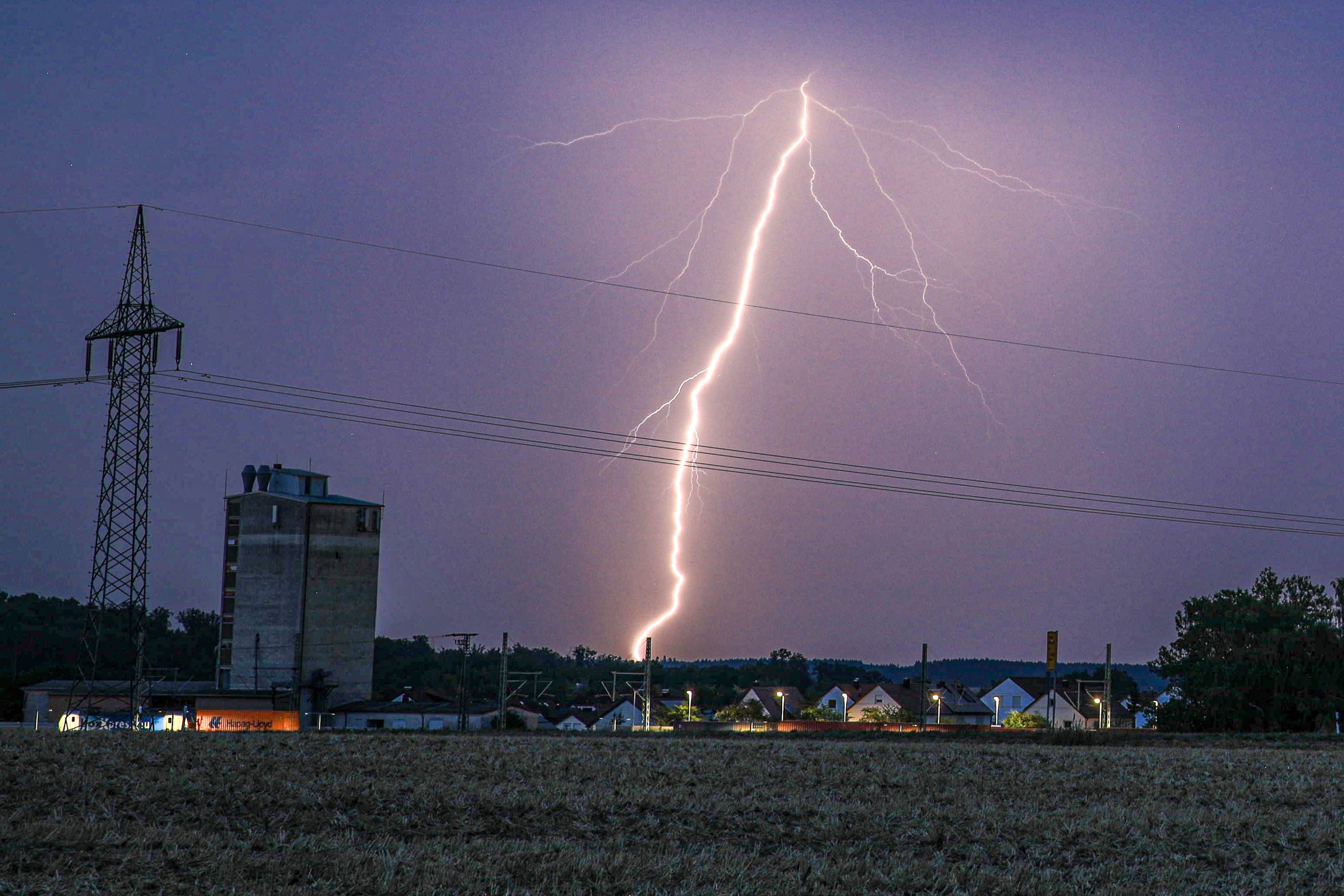 Ein Blitz erhellt bei einem abendlichen Sommergewitter den Himmel.