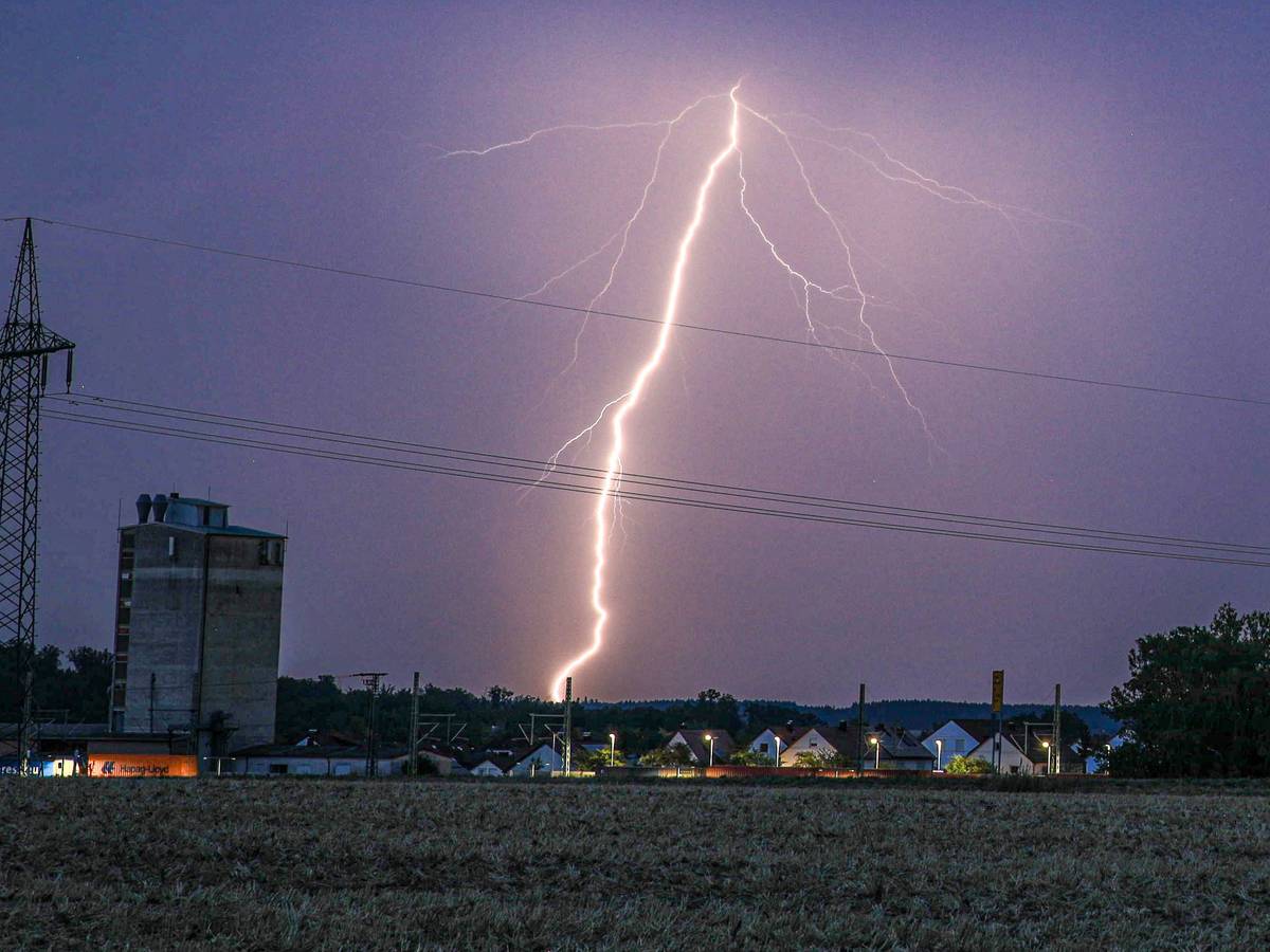 Ein Blitz erhellt bei einem abendlichen Sommergewitter den Himmel.
