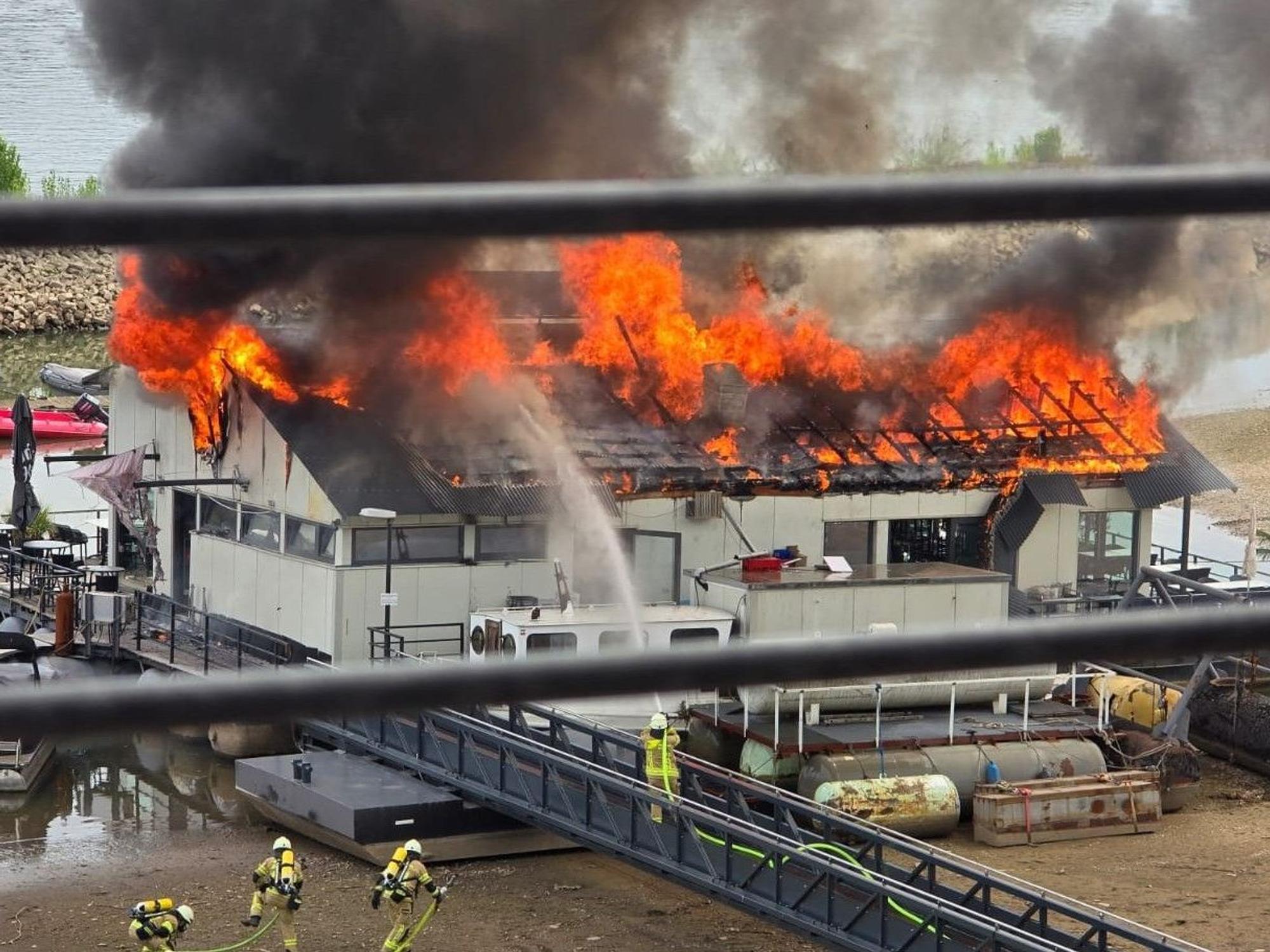 Das Dach des Sürther Bootshauses steht in Flammen.