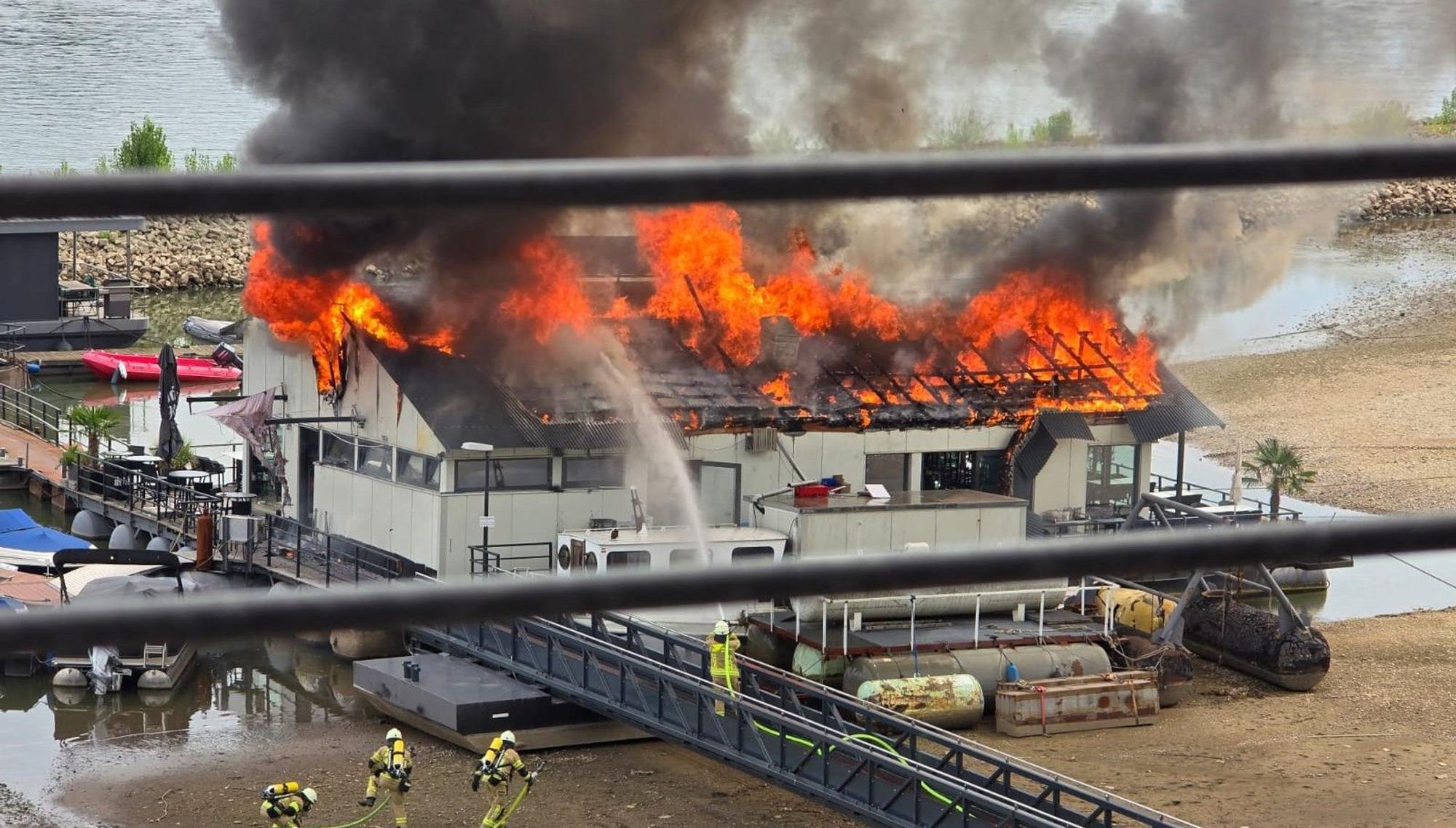 Flammen schlagen aus dem Dach des Sürther Bootshauses.