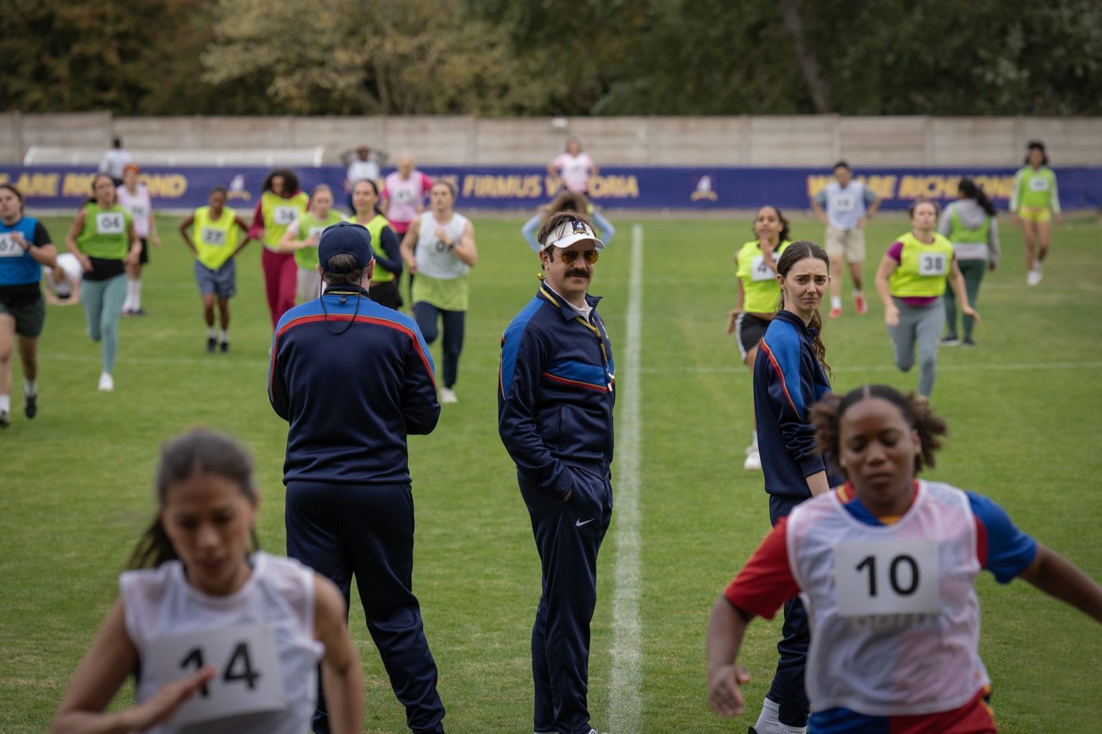 Den Lady Greyhounds gehen die Spielerinnen aus: Ted Lasso (Jason Sudeikis) und Coach Alice Chilton (Tanya Reynolds) ergreifen ungewöhnliche Maßnahmen, um den Kader aufzufüllen. (Bild: © Apple TV / Collin Hutton)