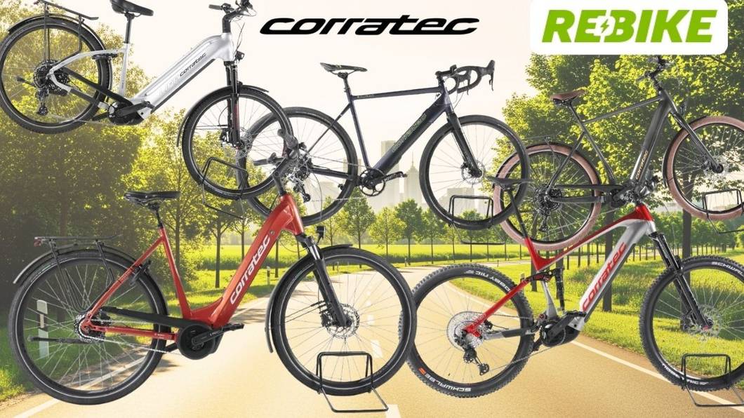 Mehrere Corratec E‑Bikes unterschiedlicher Typen – darunter Trekking-, City- und Mountainbikes – vor einer Landstraße an einem sonnigen Tag in Natur.