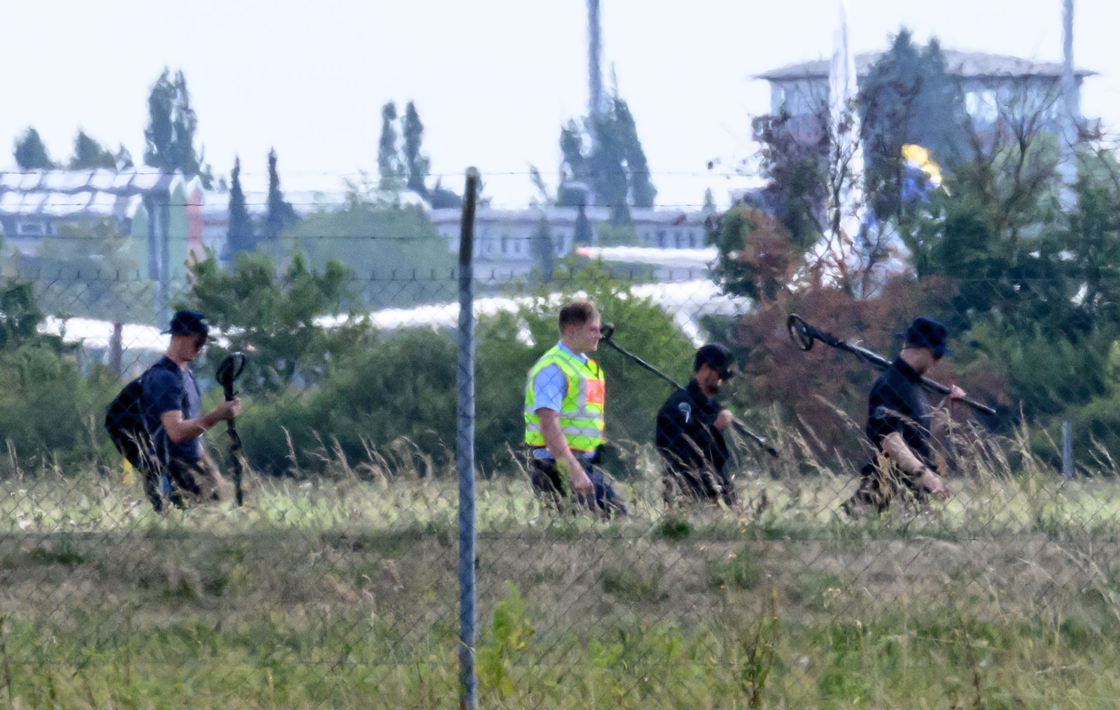Einsatzkräfte der Polizei sind mit Metalldetektoren abseits der Landebahn Nord auf dem Gelände des Flughafens Leipzig/Halle unterwegs.