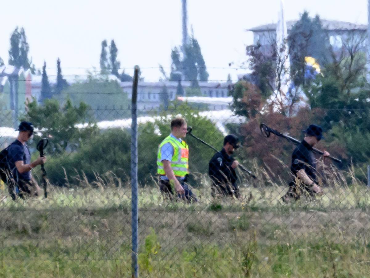 Einsatzkräfte der Polizei sind mit Metalldetektoren abseits der Landebahn Nord auf dem Gelände des Flughafens Leipzig/Halle unterwegs.