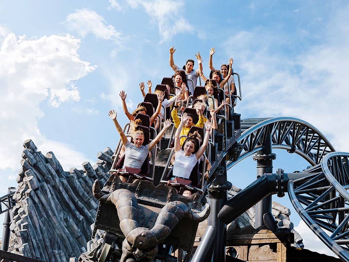 Auf einer Achterbahn reißen die Mitfahrenden die Hände hoch.