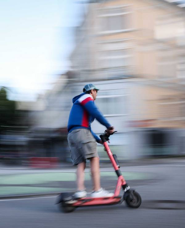 Ein Mann ist auf einem E-Scooter unterwegs (Aufnahme mit langer Verschlusszeit).
