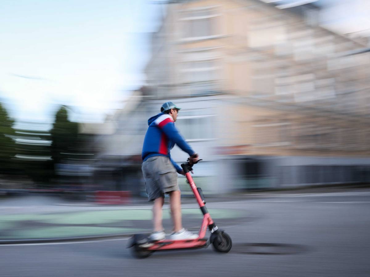 Ein Mann ist auf einem E-Scooter unterwegs (Aufnahme mit langer Verschlusszeit).