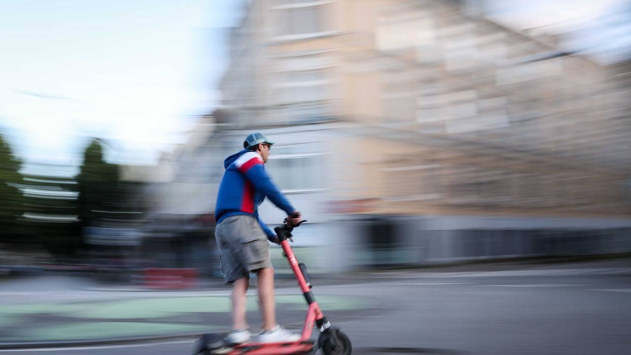 Ein Mann ist auf einem E-Scooter unterwegs (Aufnahme mit langer Verschlusszeit).