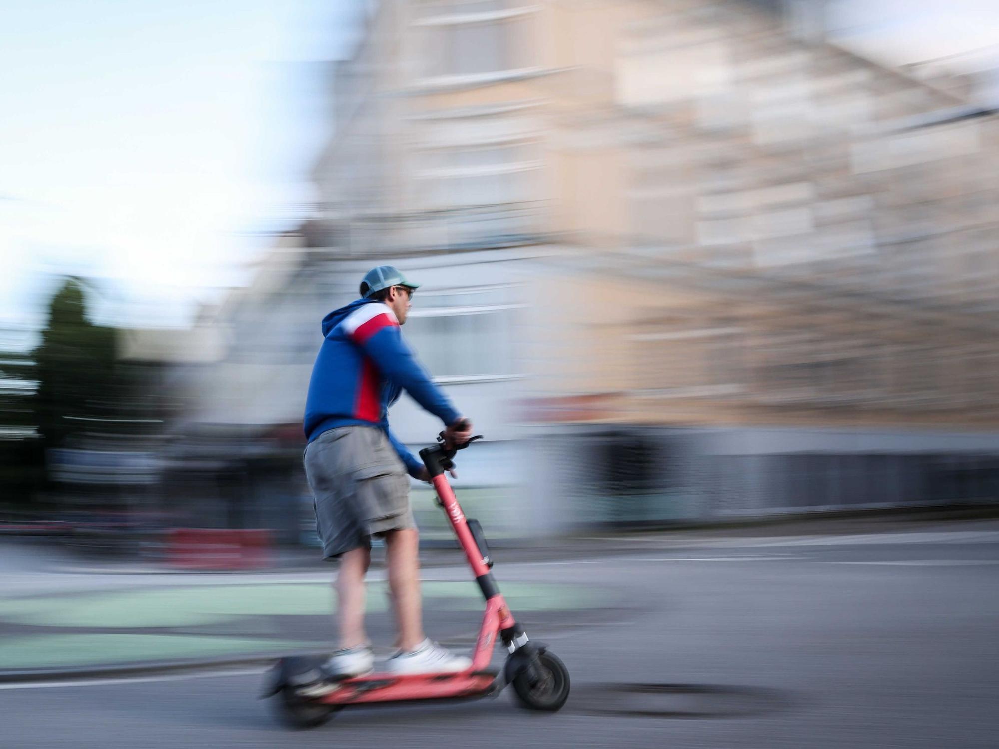 Ein Mann ist auf einem E-Scooter unterwegs (Aufnahme mit langer Verschlusszeit).