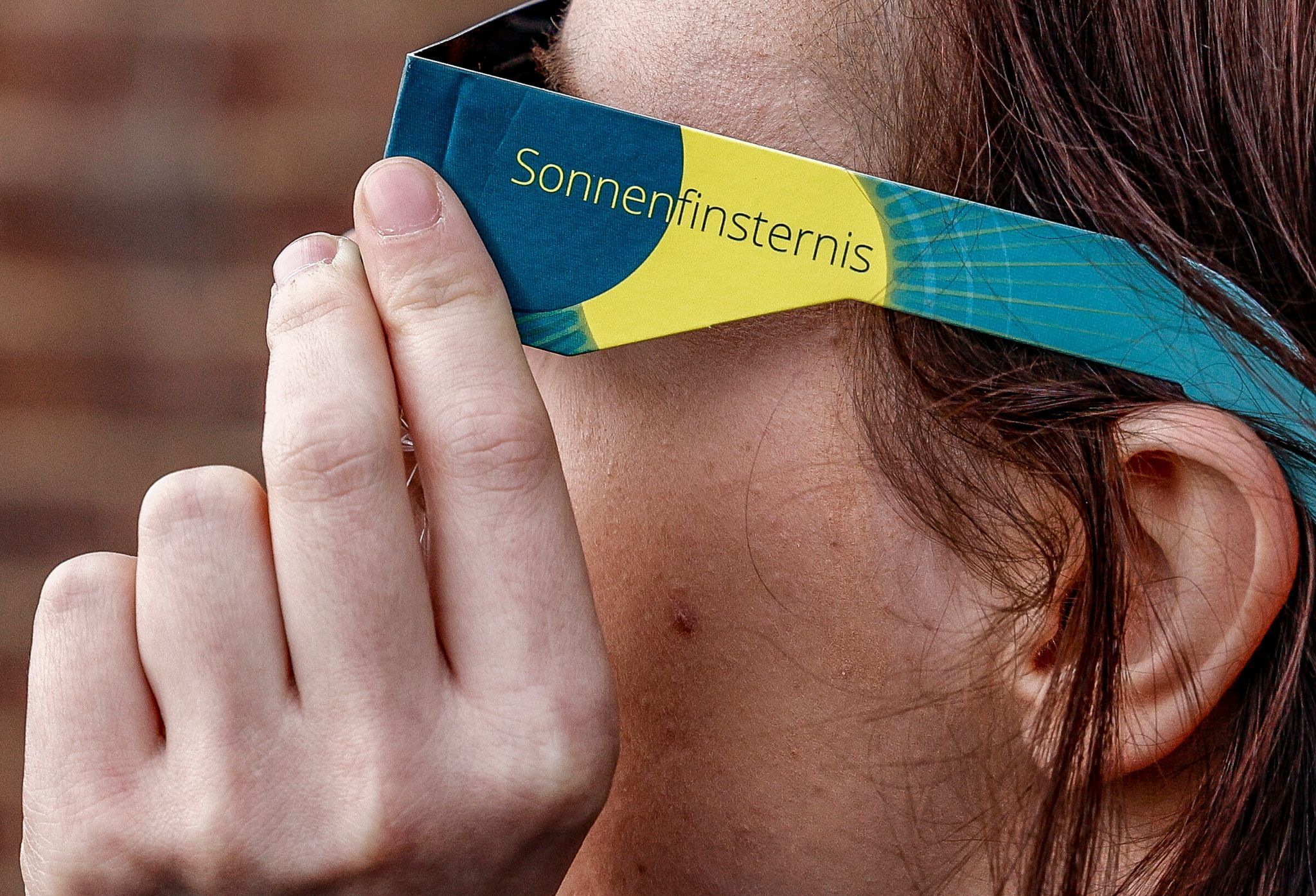 Frau mit Schutzbrille betrachtet eine partielle Sonnenfinsternis