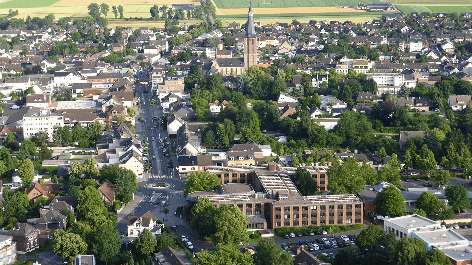Luftbild einer Stadt mit Felder und Wiesen im Hintergrund