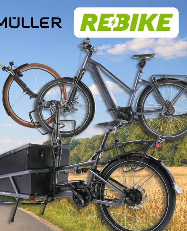 Riese & Müller E-Bike Modelle wie City-Bike, Mountian Bike und Lastenrad an einem sonnigen Tag vor einer Landstraße mit Wiesen, Feldern und Wald.