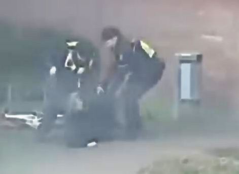 Das Bild zeigt eine Szene aus einem Video und zeigt zwei Polizisten, die auf einen Mann einprügeln.