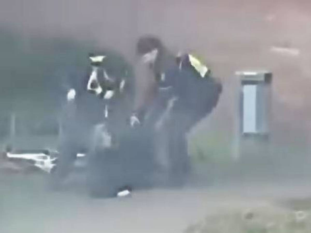 Das Bild zeigt eine Szene aus einem Video und zeigt zwei Polizisten, die auf einen Mann einprügeln.