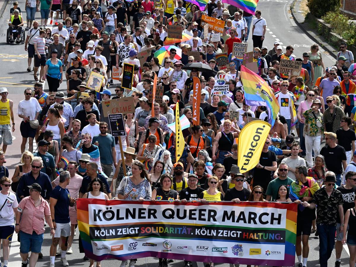 Menschen ziehen über eine Straße, die vorderen halten ein Transparent mit der Aufschrift: Kölner Queer March, Köln zeigt Solidarität, Köln zeigt Haltung.