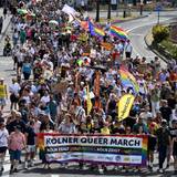 Menschen ziehen über eine Straße, die vorderen halten ein Transparent mit der Aufschrift: Kölner Queer March, Köln zeigt Solidarität, Köln zeigt Haltung.