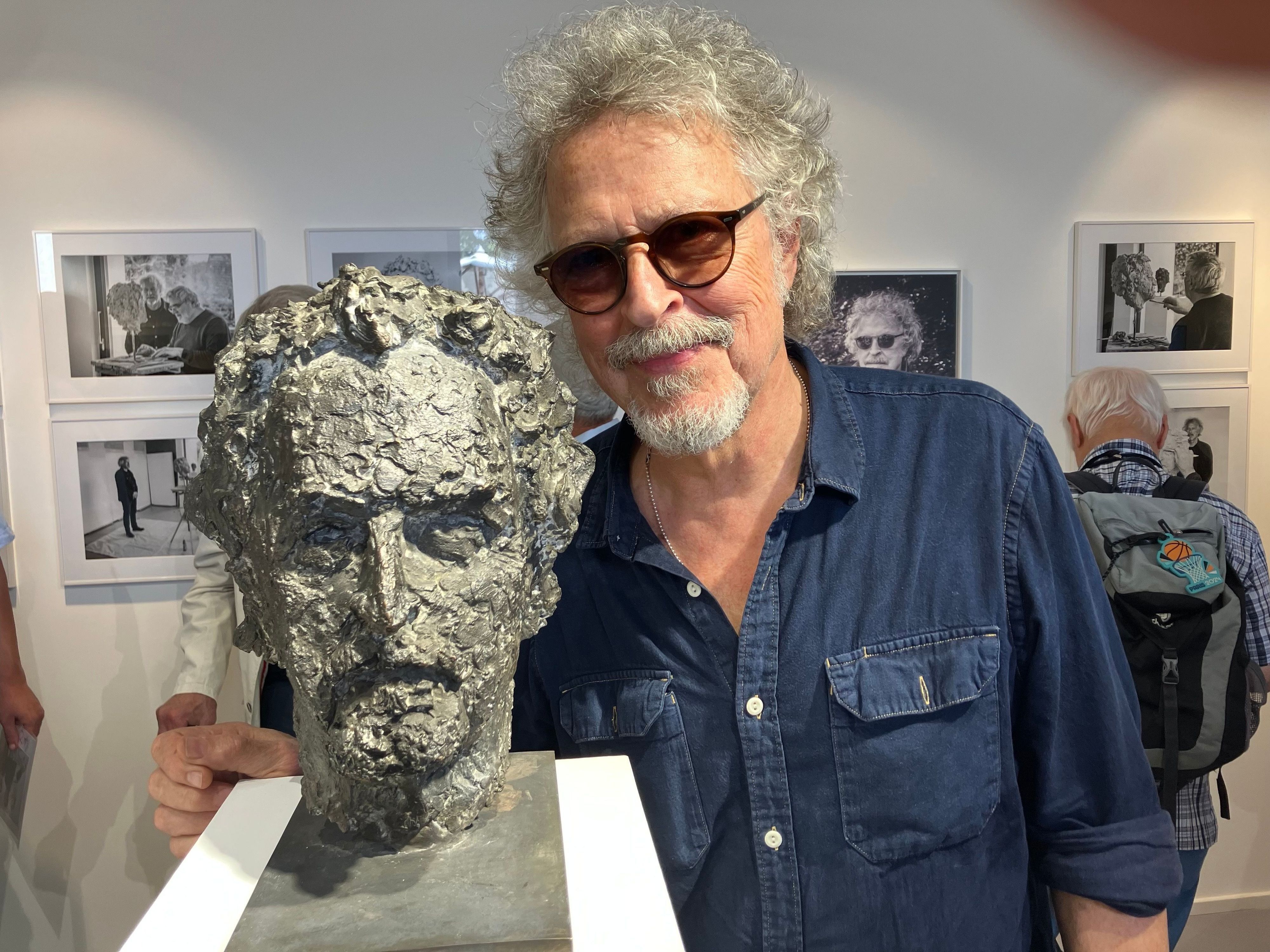 Wolfgang Niedecken steht bei der Eröffnung einer Vernissage neben seinem Bronze-Kopf.