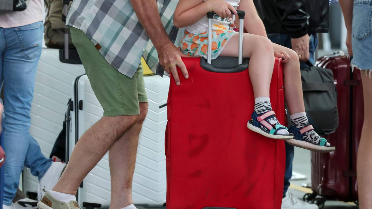 Ein Mann schiebt einen Koffer mit einem Kind zum Check-in. (Symbolfoto)