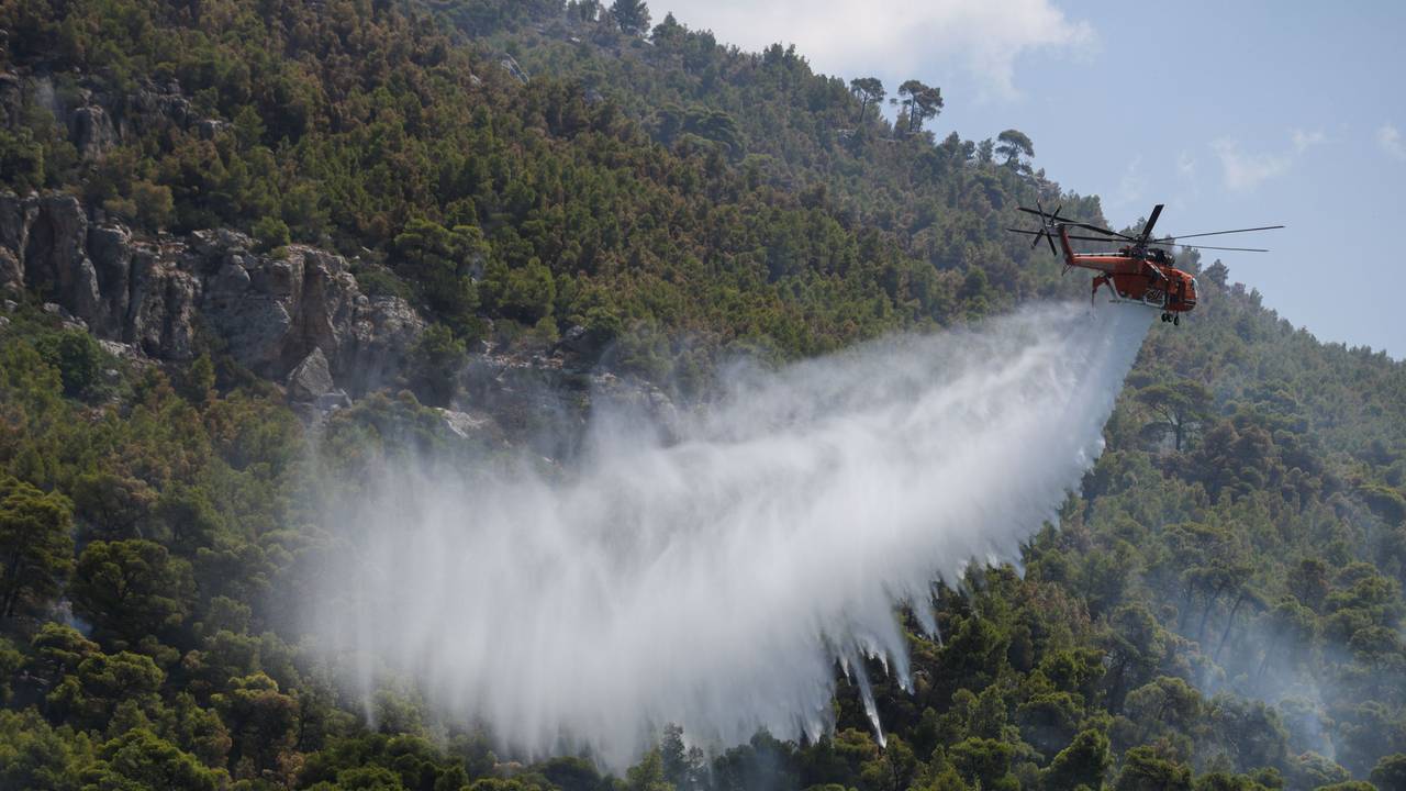 Ein Löschhubschrauber wirft Wasser über einem Wald nahe dem Dorf Loumpa ab.