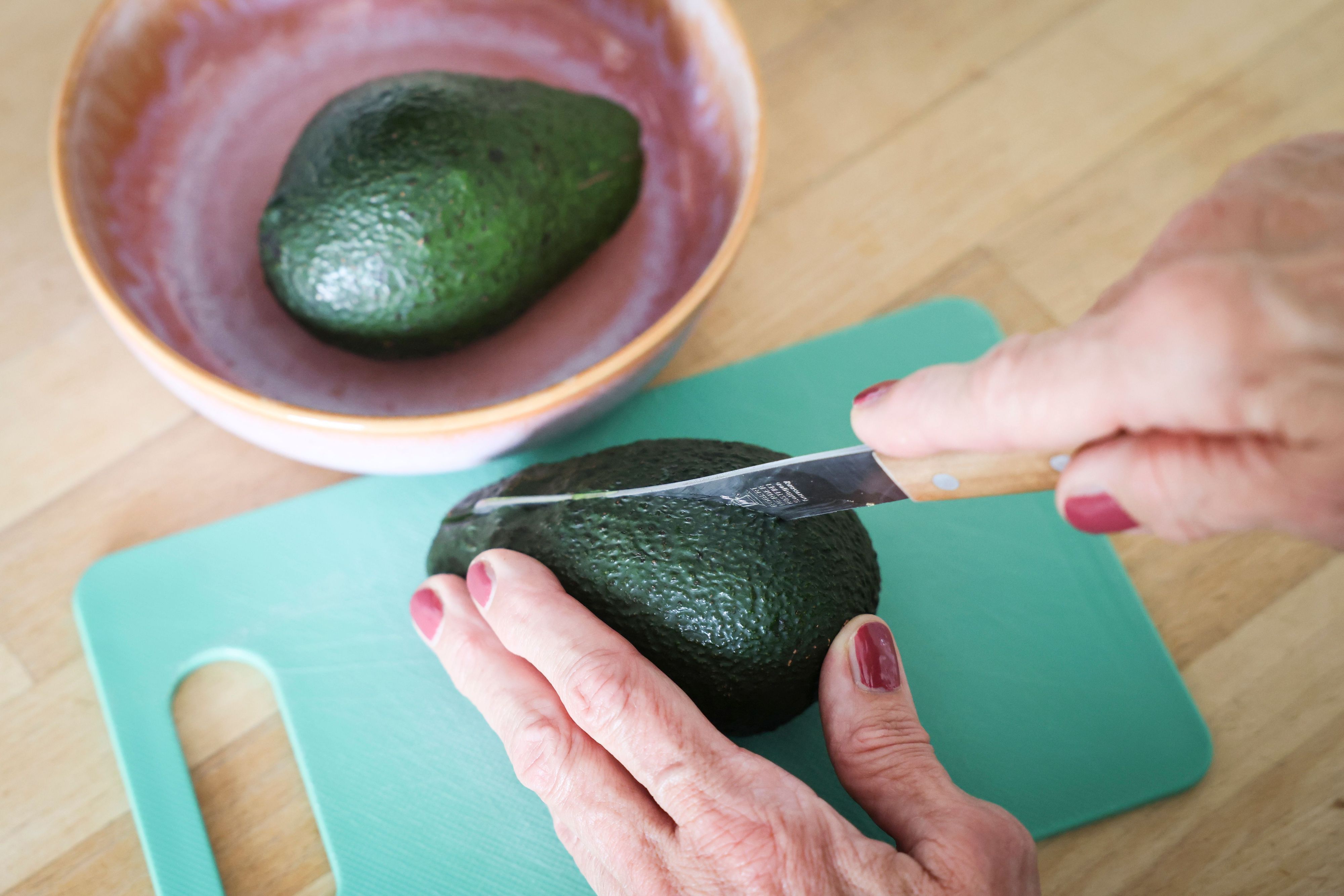 Eine Frau schneidet mit einem Messer eine Avocado auf. Die Zahlen zu Fällen von Schnittverletzungen beim Aufschneiden von Avocados sind gestiegen. (Symbolfoto)